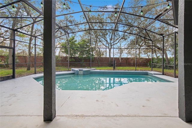 view of swimming pool featuring glass enclosure, a patio area, a fenced backyard, and a pool with connected hot tub