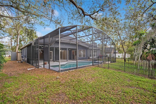 rear view of house with glass enclosure, a fenced in pool, fence, and a lawn