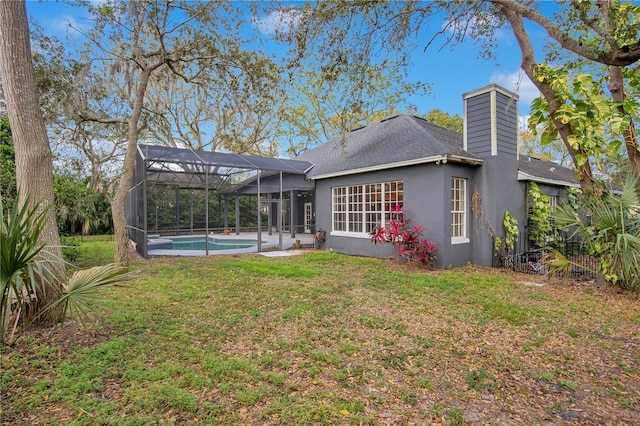 rear view of house featuring a lanai, an outdoor pool, a yard, stucco siding, and a chimney