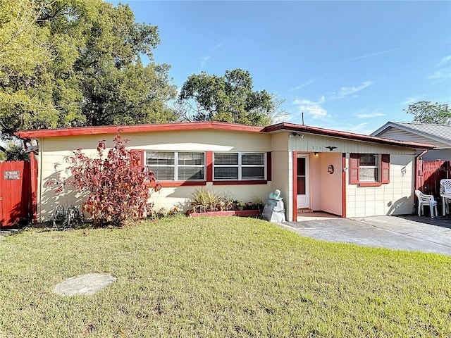 ranch-style home featuring a front yard, fence, and a patio