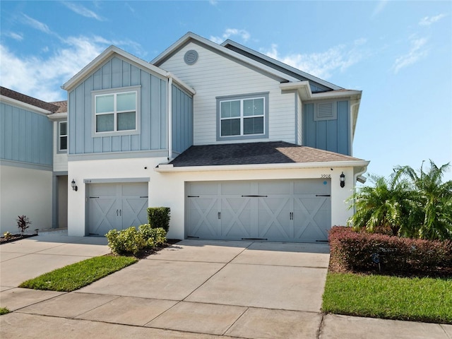 view of front of home featuring driveway, a shingled roof, an attached garage, and board and batten siding