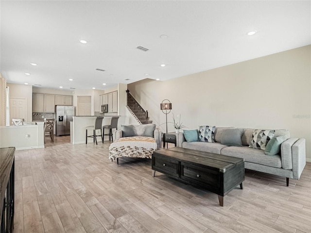 living room with recessed lighting, stairway, visible vents, and light wood-style floors