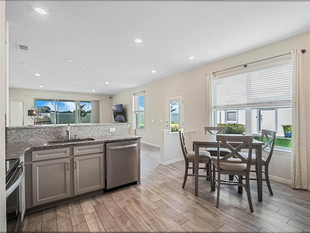 kitchen featuring a sink, light wood-style floors, electric range oven, visible vents, and dishwasher