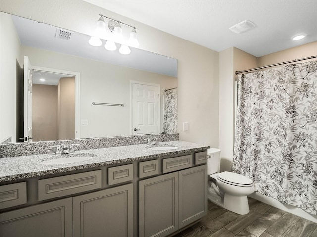 bathroom featuring toilet, a sink, wood finished floors, and visible vents