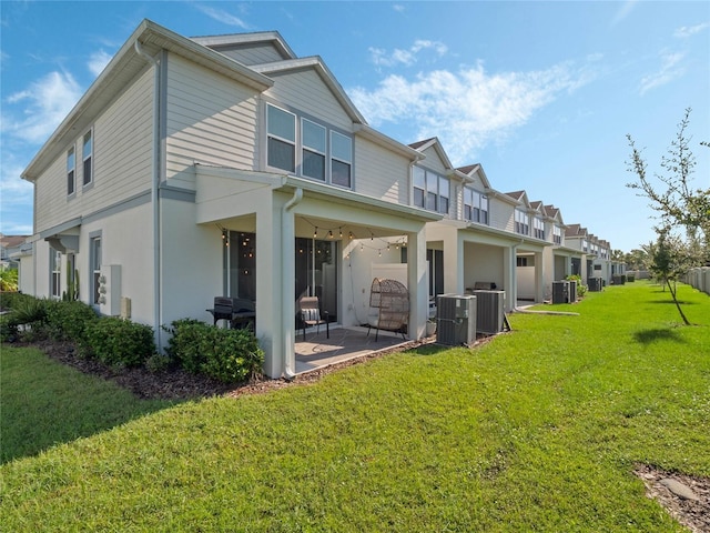 rear view of property with a patio, central AC, stucco siding, a residential view, and a lawn