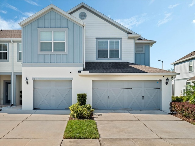 view of front of property with driveway, an attached garage, a shingled roof, and board and batten siding