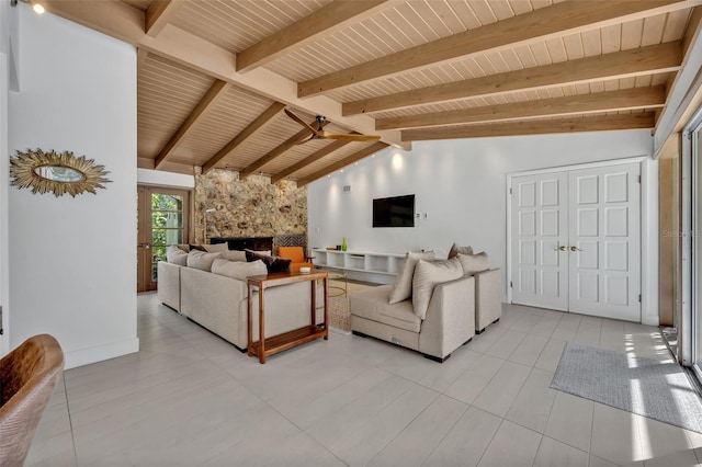 living room featuring vaulted ceiling with beams, light tile patterned floors, wood ceiling, and a stone fireplace