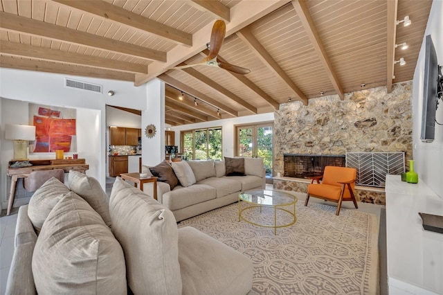 living area featuring lofted ceiling with beams, ceiling fan, a stone fireplace, wood ceiling, and visible vents