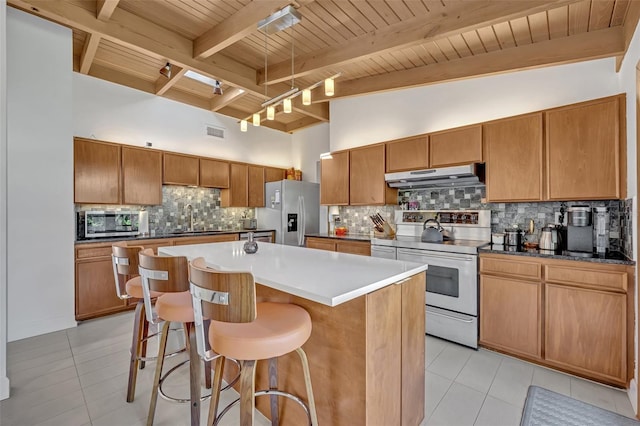 kitchen featuring under cabinet range hood, a sink, visible vents, a kitchen breakfast bar, and appliances with stainless steel finishes