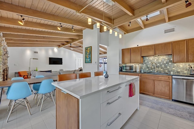 kitchen with stainless steel appliances, visible vents, backsplash, a sink, and vaulted ceiling with skylight