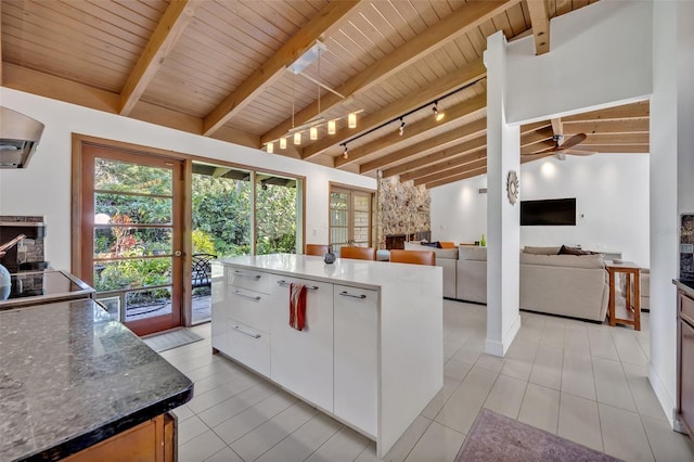 kitchen featuring lofted ceiling with beams, wooden ceiling, rail lighting, and white cabinetry