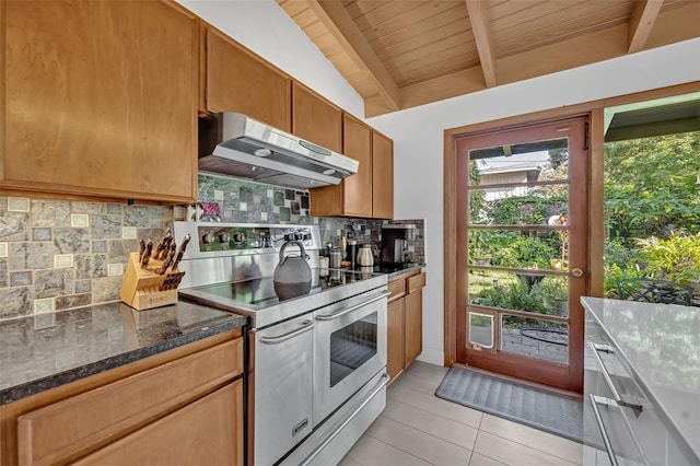 kitchen featuring light tile patterned floors, range with two ovens, decorative backsplash, lofted ceiling with beams, and under cabinet range hood