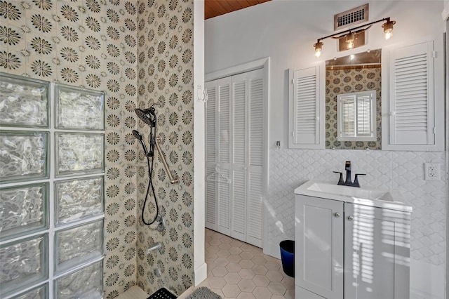 full bathroom featuring a walk in shower, tile patterned flooring, vanity, visible vents, and a closet