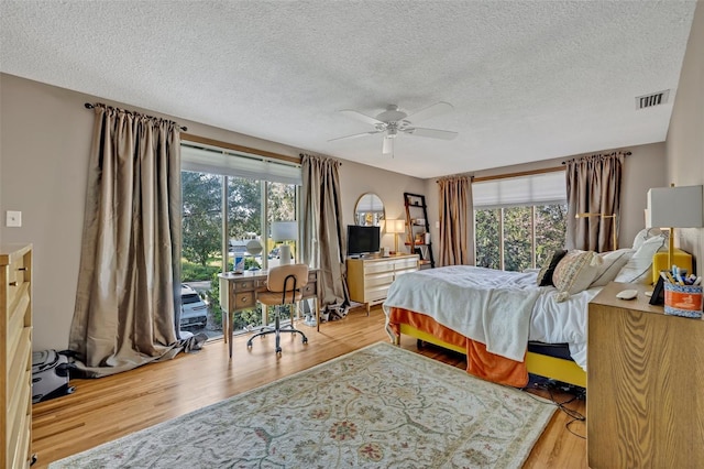 bedroom featuring multiple windows, wood finished floors, visible vents, and a ceiling fan