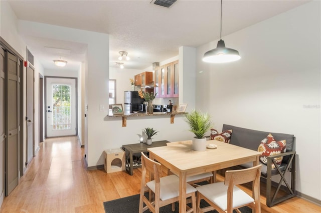 dining area featuring light wood-style floors, visible vents, and baseboards