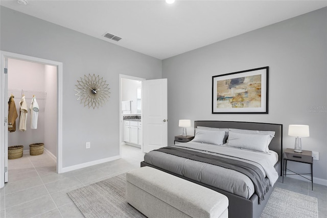 bedroom featuring light tile patterned flooring, connected bathroom, visible vents, and baseboards