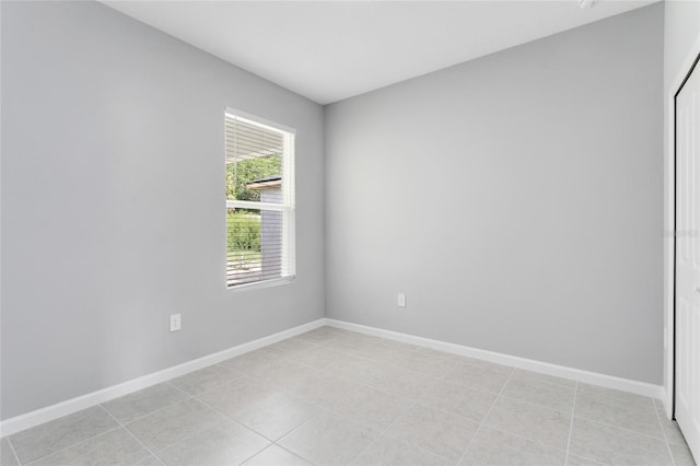 empty room with light tile patterned floors and baseboards