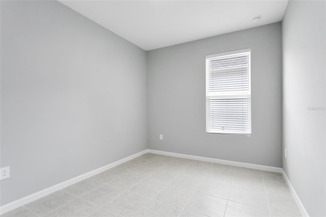 spare room featuring baseboards and light tile patterned flooring