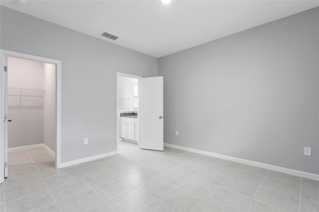 unfurnished bedroom with baseboards, visible vents, a walk in closet, and a closet