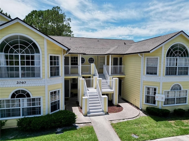 view of front of house featuring roof with shingles and stairway