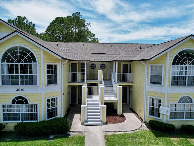 view of front facade with a shingled roof and stairway