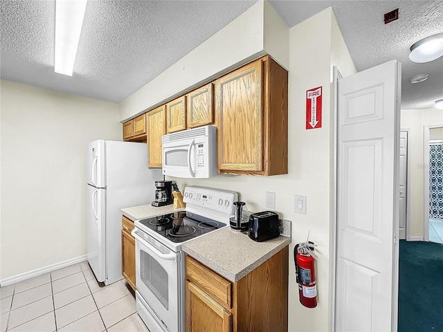 2040 Royal Bay Blvd Unit 30, Kissimmee, FL 34746 - kitchen featuring light tile patterned floors, a textured ceiling, white appliances, light countertops, and brown cabinetry
