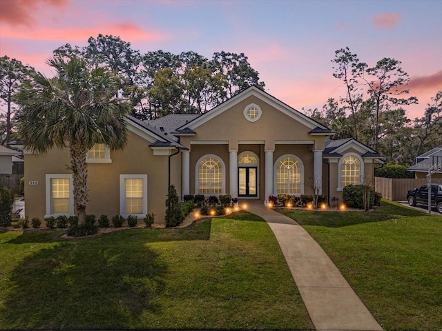 view of front of house featuring a front lawn, fence, and stucco siding