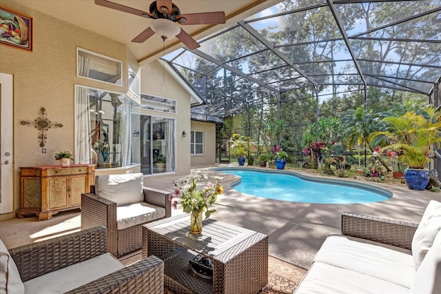 outdoor pool with a ceiling fan, glass enclosure, a patio, and an outdoor living space