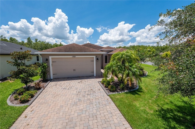 single story home featuring a front yard, decorative driveway, an attached garage, and stucco siding