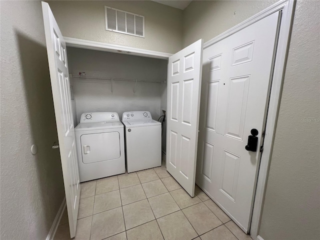 washroom featuring laundry area, washing machine and dryer, visible vents, and light tile patterned flooring