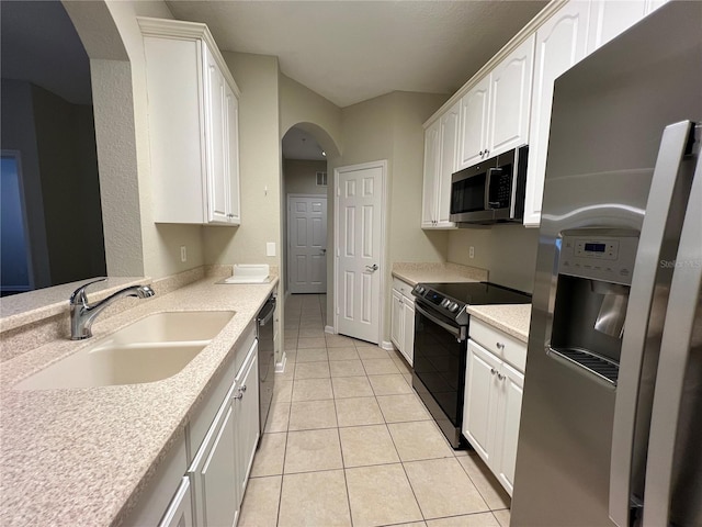 kitchen with light tile patterned floors, stainless steel appliances, a sink, and white cabinets