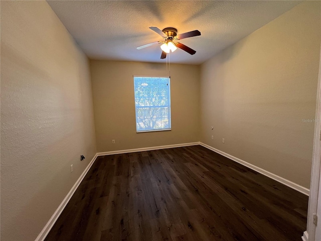 empty room with a textured ceiling, dark wood-type flooring, a ceiling fan, and baseboards