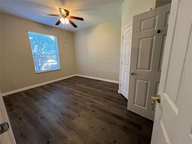 unfurnished room with dark wood-style flooring, ceiling fan, and baseboards