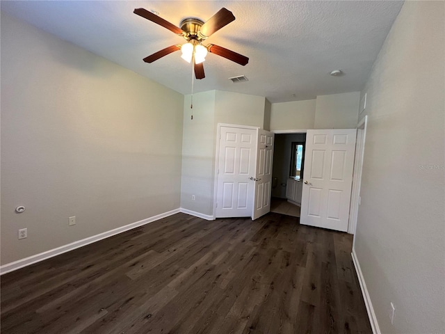 unfurnished bedroom with dark wood-style flooring, visible vents, a ceiling fan, a textured ceiling, and baseboards