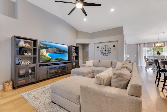 living room featuring a fireplace, lofted ceiling, recessed lighting, light wood-style floors, and ceiling fan