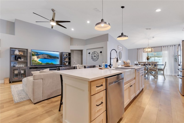 kitchen with light wood finished floors, a center island with sink, dishwasher, light countertops, and a sink