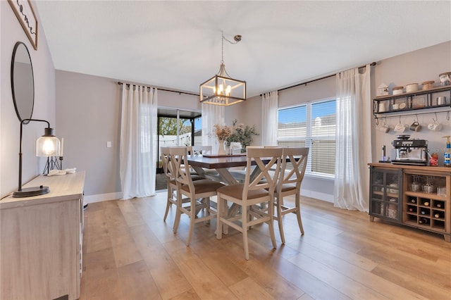 dining space featuring a chandelier, light wood-type flooring, and a healthy amount of sunlight