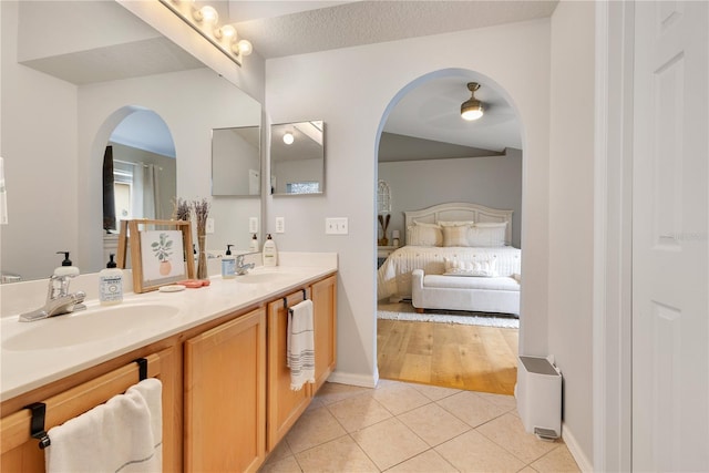 full bath with connected bathroom, double vanity, a sink, and tile patterned floors