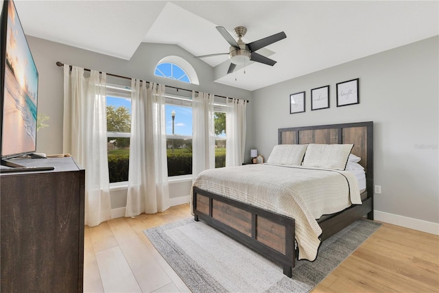 bedroom featuring light wood-style floors, baseboards, vaulted ceiling, and a ceiling fan