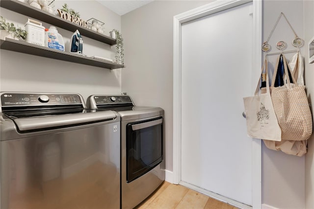 laundry room with laundry area, washer and clothes dryer, and light wood finished floors