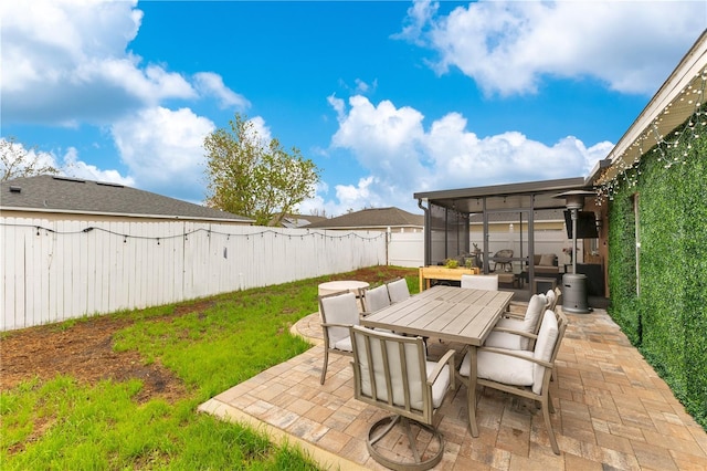 view of patio featuring outdoor dining space, a fenced backyard, and a sunroom