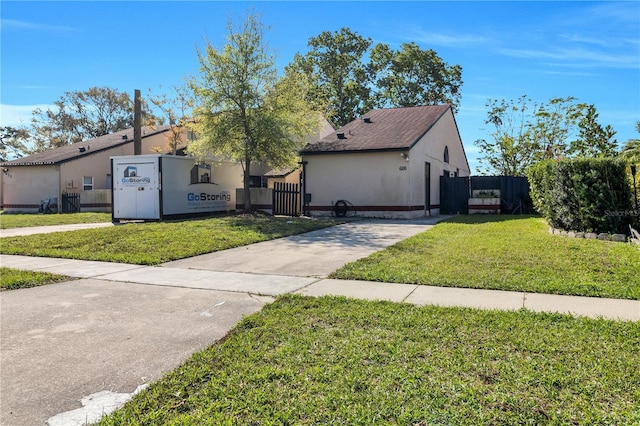 view of front facade featuring a front yard, fence, a gate, and stucco siding