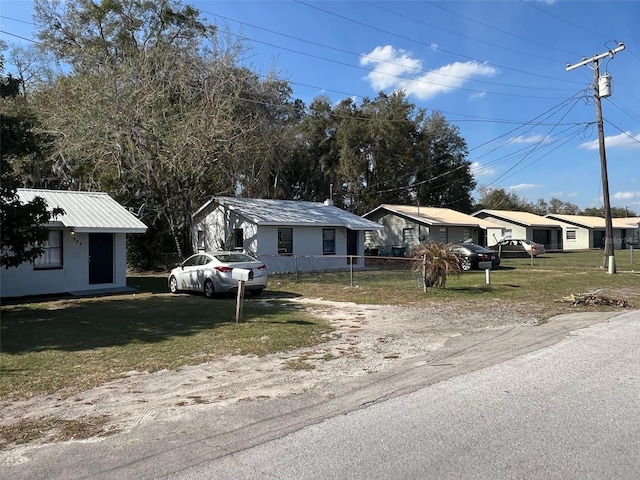 view of front of property with metal roof, fence, and a front lawn