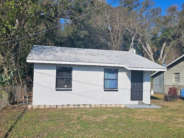 exterior space with concrete block siding and a lawn