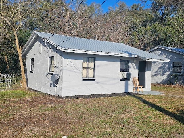 exterior space with concrete block siding, metal roof, and a front yard