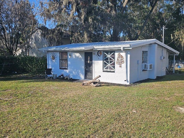 view of front of property featuring metal roof, a front lawn, cooling unit, and concrete block siding