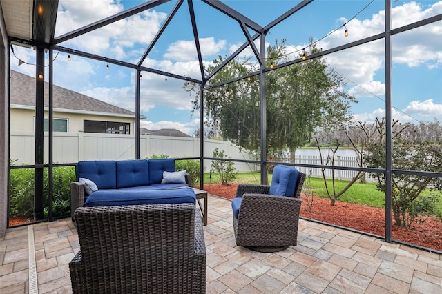 view of patio / terrace with a water view, glass enclosure, a fenced backyard, and an outdoor living space