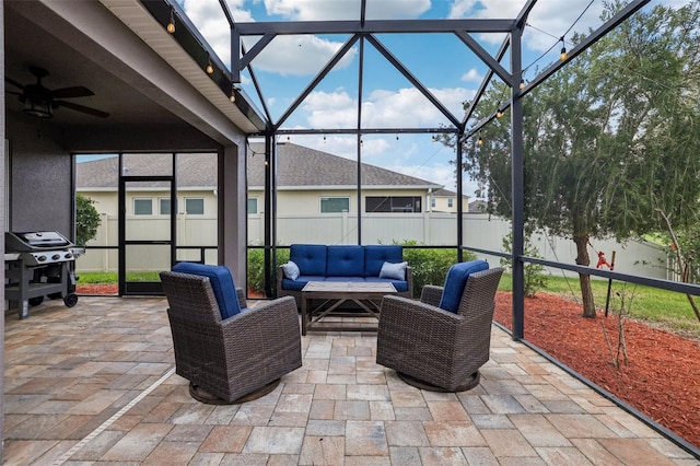 view of patio featuring glass enclosure, a fenced backyard, outdoor lounge area, and a ceiling fan