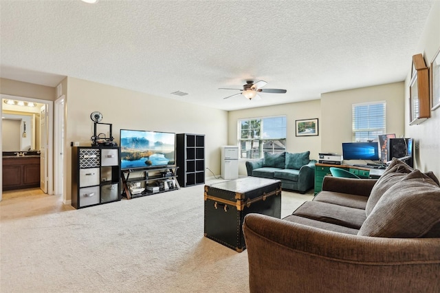 living room featuring a textured ceiling, visible vents, a ceiling fan, and light colored carpet