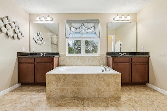 bathroom with a textured ceiling, a sink, two vanities, and a bath